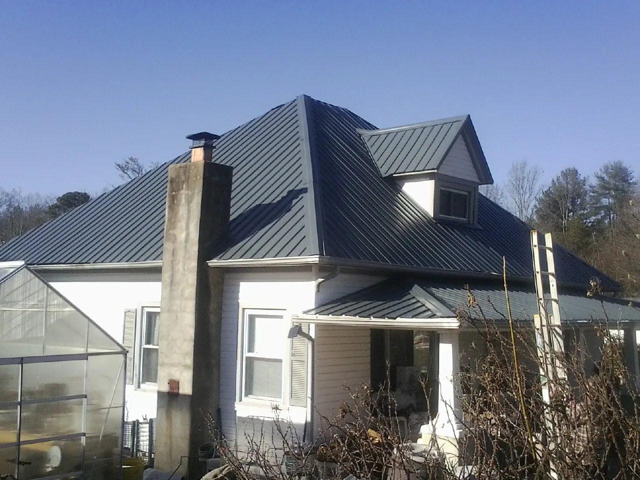 Dark blue standing seam metal roof on a white farmhouse with dormer — Slate & Tile Roof Repair by Roofing Brothers in Lock Haven