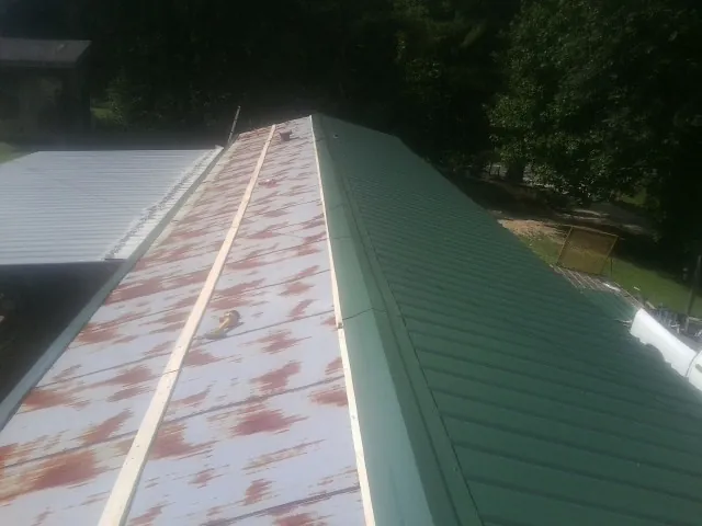 Old rusted panels beside newly installed green metal roofing — Wind Damage Roof Repair by Roofing Brothers in Lock Haven