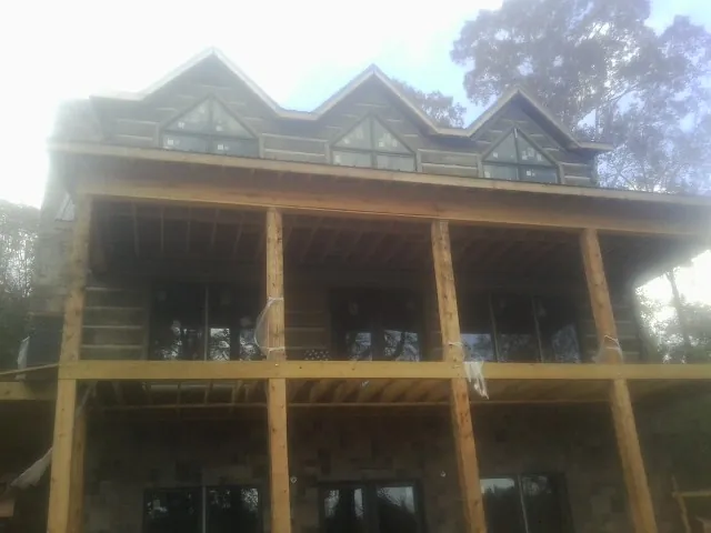 Dormers and porch framing on a large log home under construction — Roof Coating work by our crew in Lock Haven