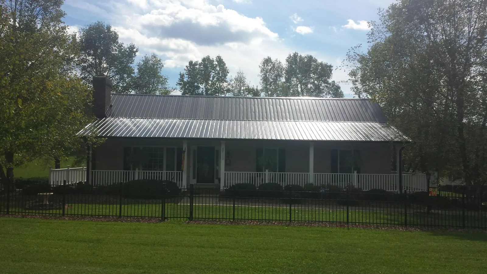 Gray metal roof on a brick ranch with a full width front porch — Gutter Guard Installation work by our crew in Lock Haven