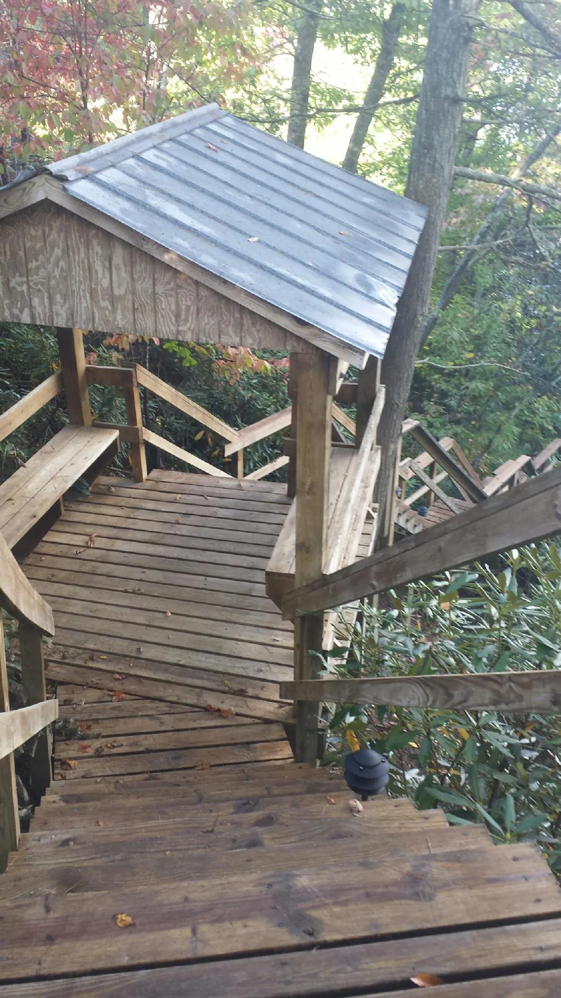 Metal roofed shelter over wooden steps on a wooded walkway — Skylight Repair & Installation work by our crew in Lock Haven