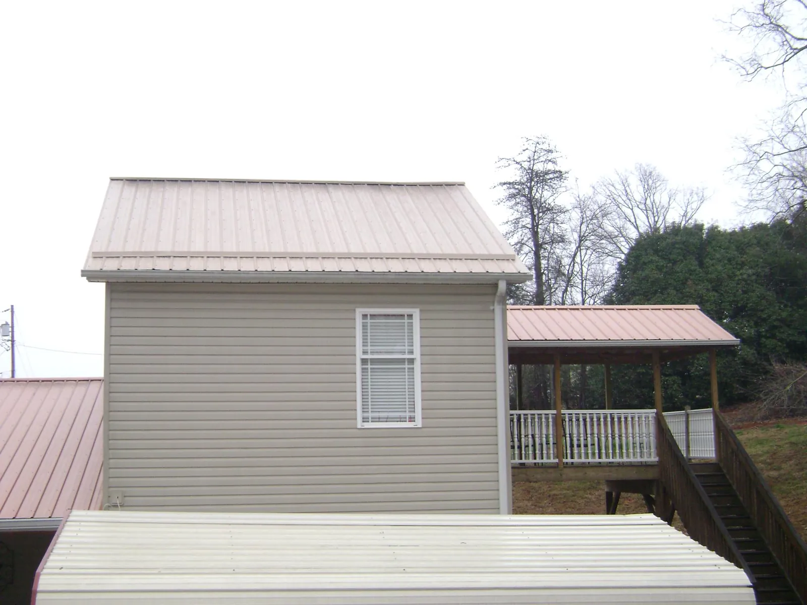 Tan metal roofs on a two story addition and attached porch, from a Roof Replacement job in Lock Haven