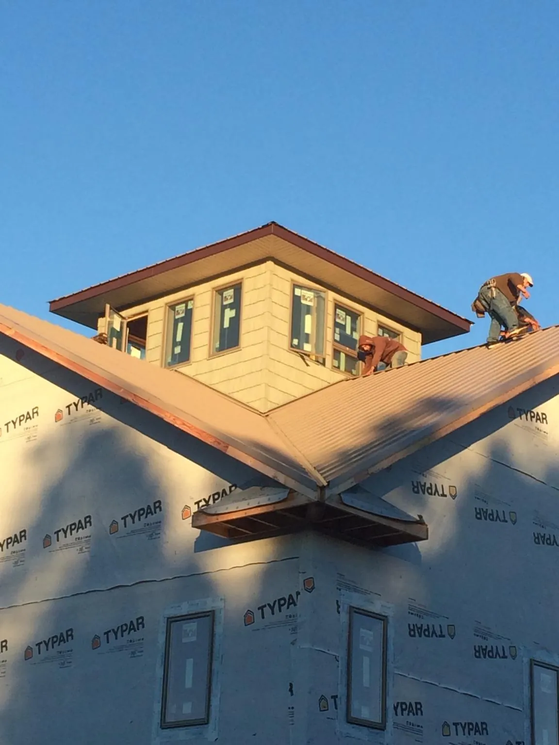 Roofers working around a rooftop cupola on a new metal roof at sunset — Roof Waterproofing in Lock Haven by Roofing Brothers